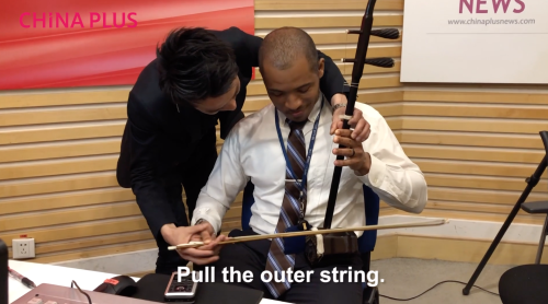 Jin Yue instructed Music Talks host Tony Reid playing the erhu. [Photo by China Plus]