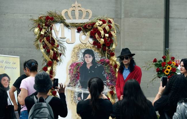 Michael Jackson impersonator Rem Garza of Long Beach, Calif., poses next to a shrine to the late pop star outside his final resting place in Holly Terrace at Forest Lawn Cemetery, Tuesday, June 25, 2019, in Glendale, Calif. Tuesday marks the 10th anniversary of Jackson's death. [Photo: AP/Chris Pizzello]