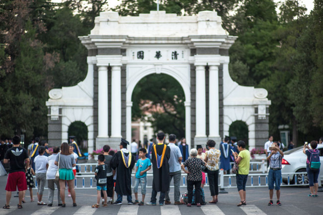 Graduates take photos in front of a gate of Tsinghua University in Beijing. [File photo: IC]
