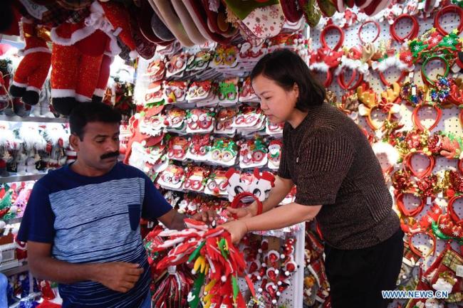 A foreign businessman(L) selects(挑选 tiāoxuǎn) Christmas commodities at the Yiwu International Trade City in Yiwu, east China's Zhejiang Province, June 26, 2019. [Photo: Xinhua]