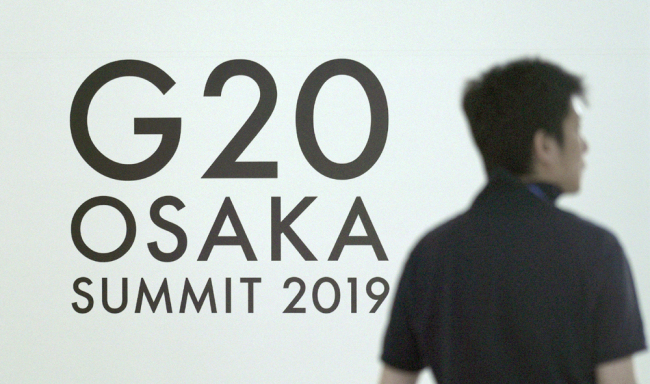 A man walks by the sign of G20 summit at the entrance of the press center of G20 summit in Osaka, Japan, on June 26, 2019. [Photo: IC]