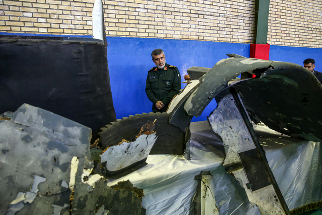 General Amir Ali Hajizadeh (C), Iran's Head of the Revolutionary Guard's aerospace division, looks at debris from a downed US drone reportedly recovered within Iran's territorial waters and put on display by the Revolutionary Guard in the capital Tehran on June 21, 2019. [File Photo: AFP/Tasnim News/Meghdad Madadi]