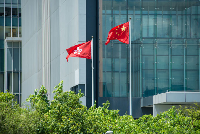 The national flag and the regional flag fly outside of government building of Hong Kong Special Administrative Region, June 17, 2015. [Photo: VCG]