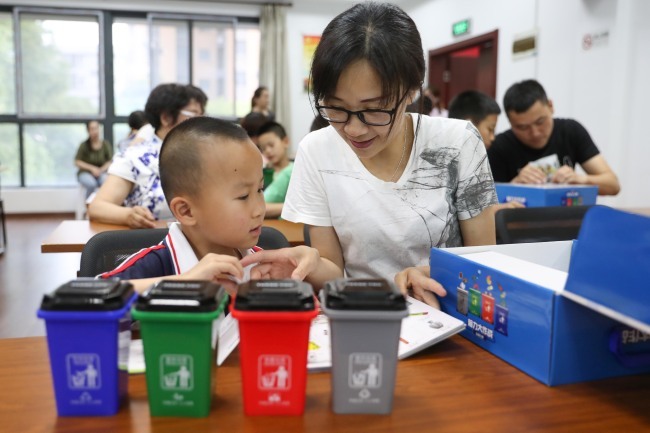 A mother teaches her son how to sort garbage in Shanghai on Sunday, June 30, 2019. [Photo: IC]