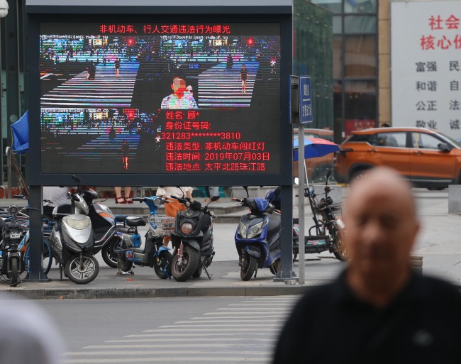 The image of a jaywalker is displayed on a giant screen next to a road in Nanjing. [Photo: IC]