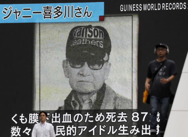 Pedestrians walk past a large screen displaying news reporting on the death of Japanese entertainment mogul Johnny Kitagawa in Tokyo, Japan, July 10, 2019. [Photo: IC]