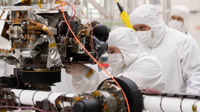 Engineers at JPL install a sensor-filled turret on the end of the rover's seven-foot-long (2.1-meter-long) robotic arm. The image was taken on July 11, 2019. [Photo: NASA/JPL-Caltech]