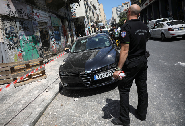 A police officer stands on a street next to a damaged car following an earthquake in Athens, Greece, July 19, 2019. [Photo: VCG/Reuters/Alkis Konstantinidis]