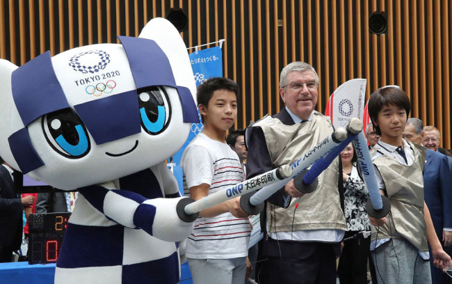 IOC President Thomas Bach (2nd R) poses for photos with Japanese junior high school student Yui Hashimoto (R), Yuto Tojima (2nd L), and Miaitowa (L), the mascot of the Tokyo 2020 Olympic Games, during an event marking one year before the start of the games in Tokyo on July 24, 2019. [Photo: Pool/Koji Sasahara]