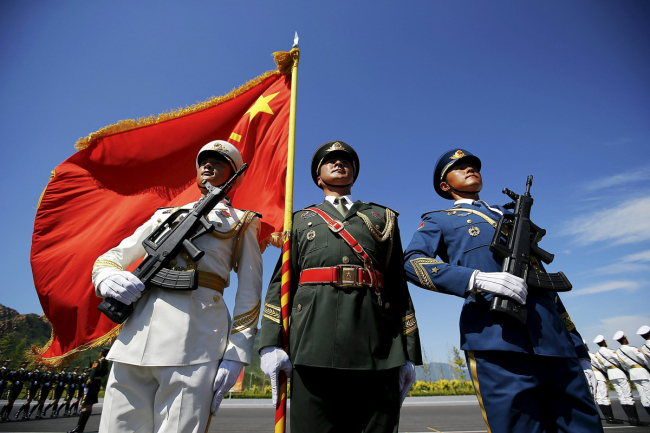 Officers and soldiers of China's People's Liberation Army hold a flag and weapons during a training session for a military parade to mark the 70th anniversary of the end of World War II, at a military base in Beijing, China, August 22, 2015. [File photo: VCG]