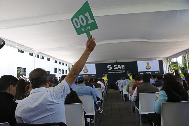 A man raises his paddle during an auction of government seized jewelry at Los Pinos Cultural Center, formerly the presidential residence, in Mexico City, Sunday, July 28, 2019. The auction was held by the Institute to Return the Stolen to the People, the name for a branch of the Finance Ministry charged with selling property seized from purported drug dealers and tax cheats, as well as government goods that are no longer in use. [Photo: AP/Ginnette Riquelme]