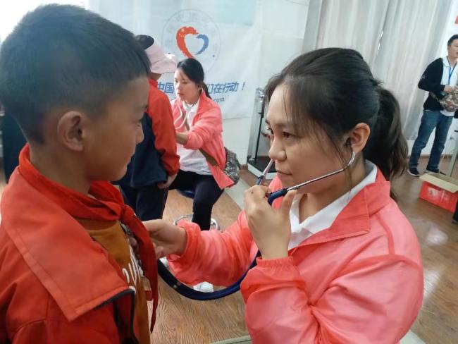 Doctor Li uses a stethoscope to check whether a student has a heart murmur during the screening. [Photo: from China Plus] 