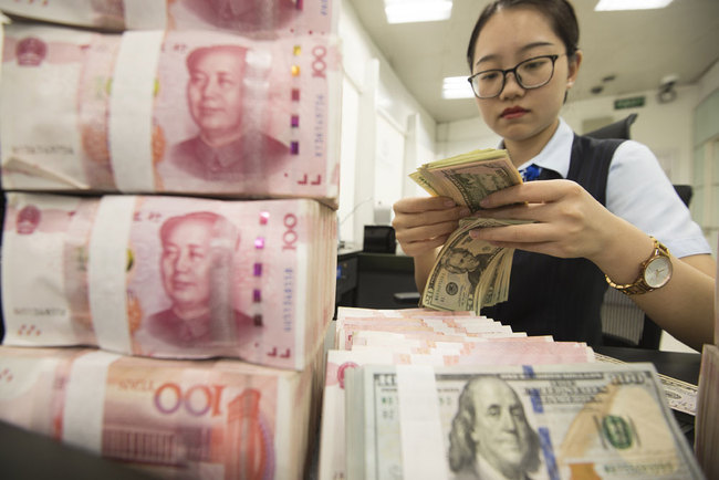 A bank clerk count banknotes of China's yuan and U.S. dollars in a bank in Jiangsu Province on Tuesday, August 6, 2019. [Photo: VCG]