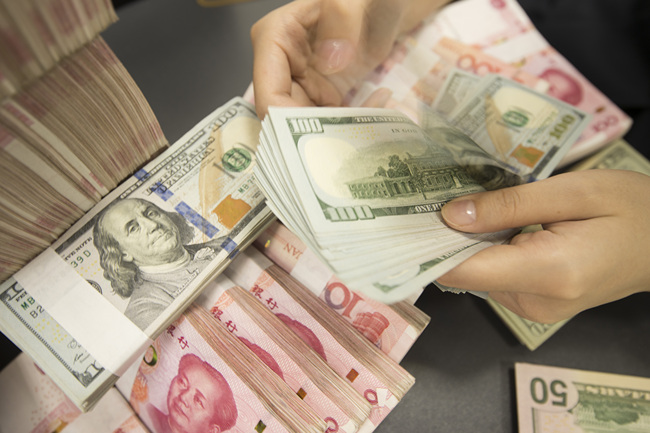 A bank clerk count banknotes of China's yuan and U.S. dollars in a bank in Jiangsu Province on Tuesday, August 6, 2019. [Photo: VCG]