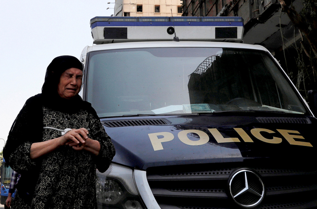 An Egyptian woman cries as she walks past a police car in front of the damaged facade of the National Cancer Institute, after an overnight fire from a blast, in Cairo, Egypt August 5, 2019. [Photo: AMR ABDALLAH DALSH/Reuters via VCG]