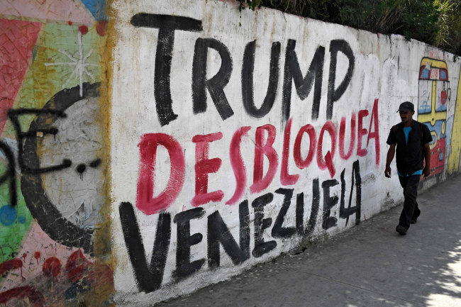 A man walks past a wall reading "Trump unblock Venezuela" in Caracas on August 6, 2019, the day after US President Donald Trump ordered a freeze on all Venezuelan government assets in the United States and barred transactions with its authorities, in Washington's latest move against Venezuelan President Nicolas Maduro. [Photo: VCG/ Federico Parra]