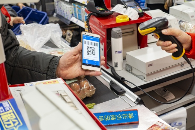 A Chinese cashier scans the QR code through mobile payment service Alipay of Alibaba Group on the smartphone of a customer at a supermarket in Shanghai, China, February 16, 2019. [File Photo: IC]