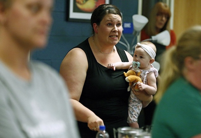 In this Aug. 22, 2019 photo, Jessica Moloney, holding her 6-month-old daughter Amelia, expresses her displeasure at a meeting at Highland High School in Marengo, Ohio, about how the school board handled a recent incident where a child had access to a gun, pointed it at another student, and that parents weren't informed. Schools across the country have faced a backlash for favoring privacy over telling parents when there are threats in their children’s classrooms.[Photo: AP]