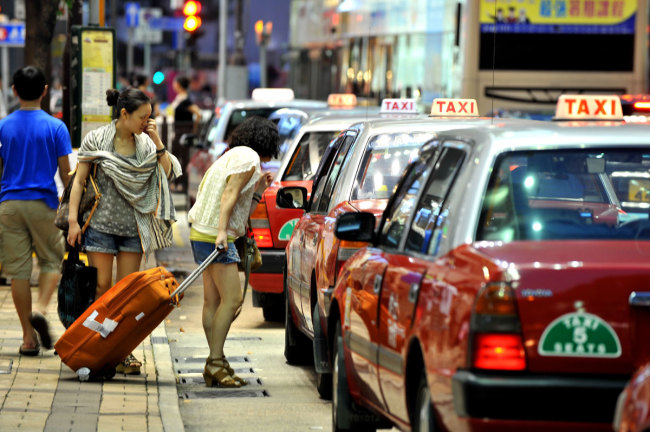 Two women talk to a taxi driver on the street in Hong Kong, China, June 28, 2012. [File Photo: IC]
