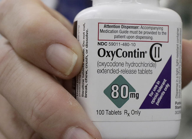 FILE - In this April 2, 2018, file photo, a pharmacist in San Francisco poses for photos holding a bottle of OxyContin. In court papers filed in New York on Sunday, Sept. 15, 2019, Purdue Pharma, the drug's manufacturer, flied for Chapter 11 bankruptcy protection. [Photo: AP/Jeff Chiu]