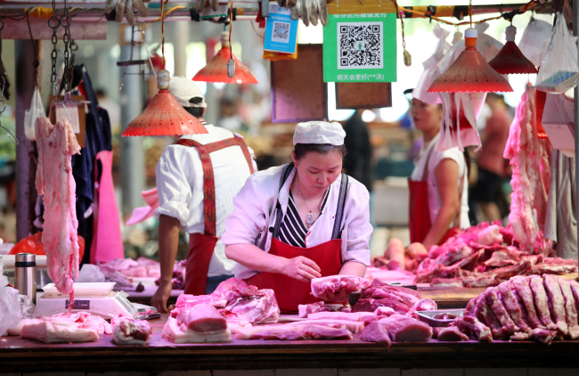 A vendor sells pork and other meat products at her stalls in a free market in Kunming, Yunnan Province, June 29, 2019. [Photo: IC]