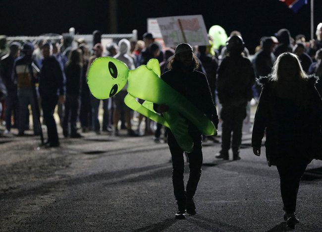 A mans holds an inflatable alien at an entrance to the Nevada Test and Training Range near Area 51 Friday, Sept. 20, 2019, near Rachel, Nev. People gathered at the gate inspired by the "Storm Area 51" internet hoax. [Photo: AP/John Locher]