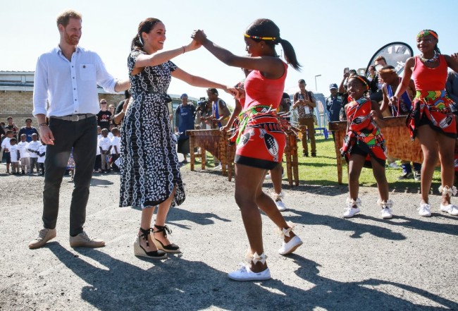 Prince Harry, Duke of Sussex and Meghan, Duchess of Sussex dance with local girls when visited the "Justice desk", an NGO in the township of Nyanga in Cape Town, as they begin their tour of the region on September 23, 2019. [Photo: AFP]