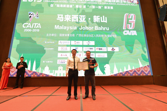 Chinese Motorsports Administration deputy director Yang Guangyu (Left) delivers the top prize award to a race winning team member at the closing ceremony of the China-ASEAN International Touring Assembly in Johor Bahru, Malaysia on Sep 25, 2019. [Photo provided to China Plus]