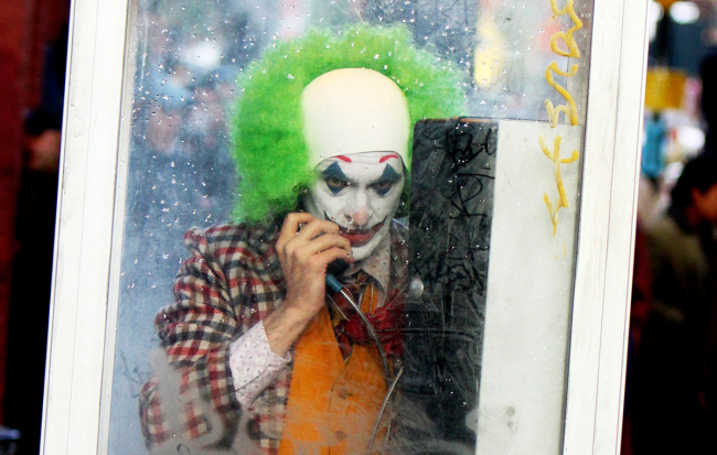 A picture taken during the movie "Joker" filming in 2018 shows actor Joaquin Phoenix with full joker makeup was in a phone booth in New York. [Photo: Startraks via IC]