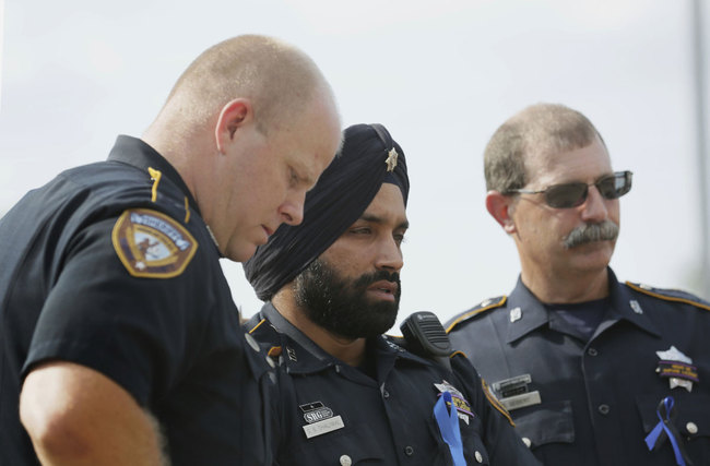 In this Aug. 30, 2015, photo, Harris County Sheriff's Deputy Sandeep Dhaliwal, center, grieves with Deputies Dixon, left, and Seibert, right, at a memorial for Deputy Darren Goforth, at the Chevron where he was killed, in Houston. [Photo: AP]