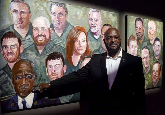 US Army Sergeant DeWitt Osborne poses next to his painting made by former US President George W. Bush at the "Portraits of Courage" exhibit at the Kennedy Center in Washington, DC on October 7, 2019. [Photo: AFP]