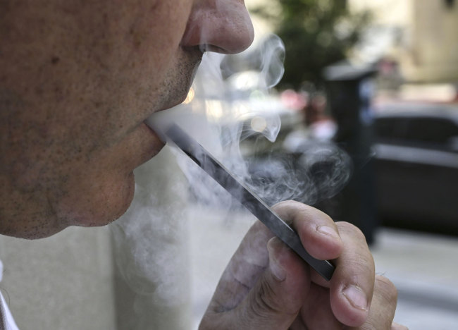 This photo illustration shows a man exhaling smoke from an electronic cigarette in Washington, DC on September 12, 2019. [Photo: AFP]