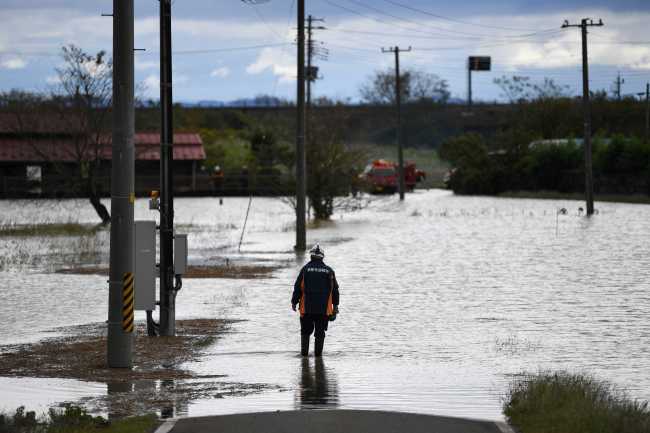 A member of Japan's Fire and Disaster Management Agency wades through floodwaters in the aftermath of Typhoon Hagibis in Kurihara city, Miyagi Prefecture on October 13, 2019. [Photo: AFP/CHARLY TRIBALLEAU]