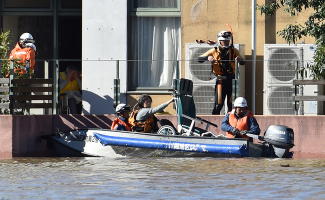 Rescue personnel use a boat to evacuate people and caregivers from the Kawagoe Kings Garden elderly care centre in Kawagoe city, Saitama prefecture on October 13, 2019. [Photo: AFP/Kazuhiro Nogi]