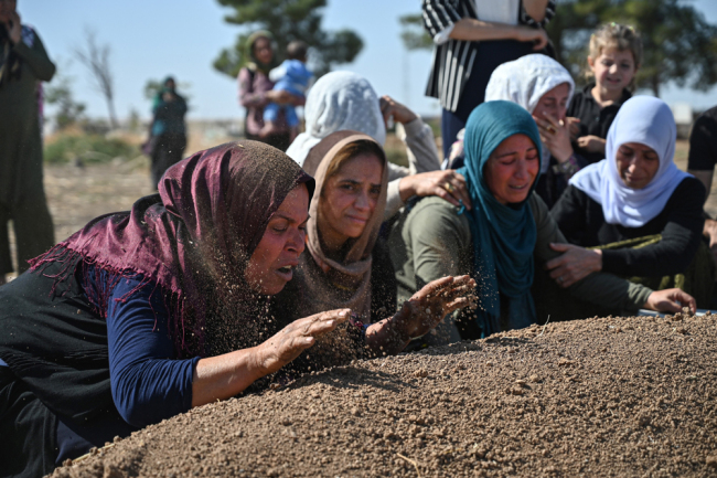 People mourn in front of the grave of Halil Yagmur who was killed in a mortar attack a day earlier in Suruc near northern Syria border, during funeral ceremony in Suruc on October 12, 2019. Ten Turkish civilians were killed in cross-border shelling on Friday, while four of Turkey's soldiers died as Ankara pressed on with its offensive against Kurdish militants in Syria. [Photo: AFP/Ozan Kose]