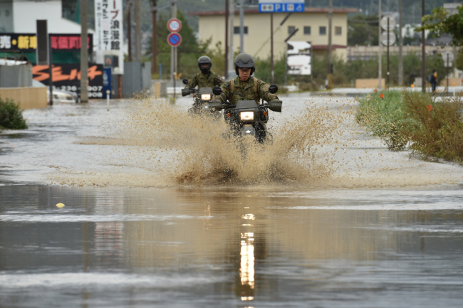 Military personnel drive their motorbikes down a flooded street in the aftermath of Typhoon Hagibis in Nagano on October 14, 2019. [Photo: AFP/Kazuhiro Nogi]
