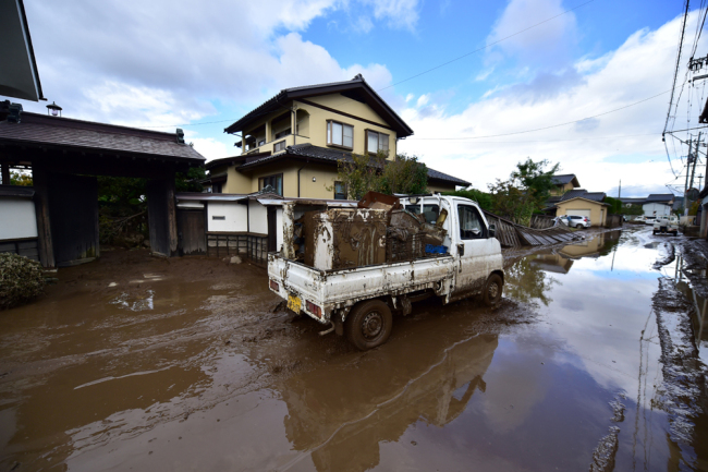 A vehicle carrying house wreckage drives through a muddy area from recent flooding caused by Typhoon Hagibis in Nagano on October 15, 2019, after the storm hit Japan on October 12 unleashing high winds, torrential rain and triggered landslides and catastrophic flooding. [Photo: AFP/Kazuhiro Nogi]