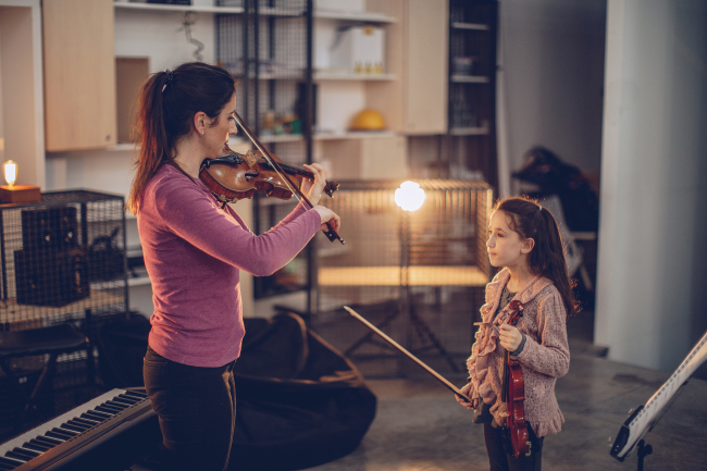 A young girl learns to play the violin. [File Photo: VCG]