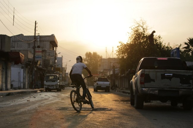 A Syrian boy rides his bicycle down a street in the Syrian border town of Tal Abyad on October 17, 2019, as Turkey and its allies continue their assault on Kurdish-held border towns in northeastern Syria. [Photo: AFP]