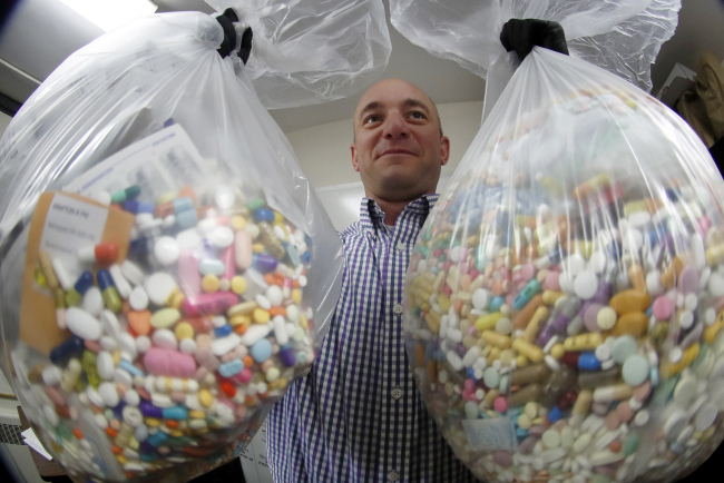 Narcotics detective Ben Hill, with the Barberton Police Department, shows two bags of medications that are are stored in their headquarters and slated for destruction in Barberton, Ohio on Sept. 11, 2019. [File photo: AP/Keith Srakocic]