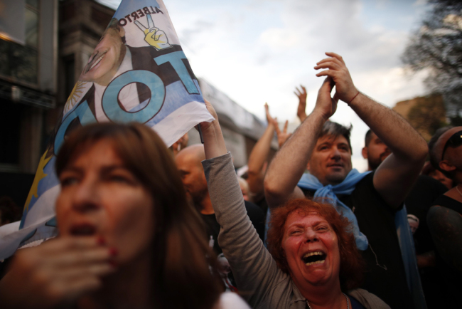 Supporters of center-left Peronist presidential candidate Alberto Fernández and running mate, former President Cristina Fernández, celebrate as they wait for election results outside their party's election headquarters in Buenos Aires, Argentina, Sunday, Oct. 27, 2019. [Photo: AP/Natacha Pisarenko]