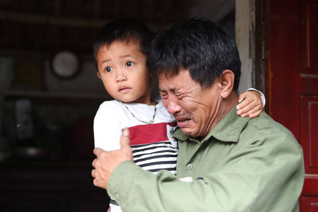 Le Minh Tuan, father of 30-year old Le Van Ha, who is feared to be among the 39 people found dead in a truck in Britain, cries while holding Ha's son outside their house in Vietnam's Nghe An province on October 27, 2019. [Photo: AFP/Nhac Nguyen]