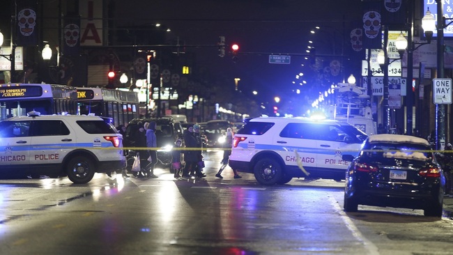 Trick-or-treaters walk past a crime scene in the 3700 block of West 26th Street, where a 7-year-old girl was shot while trick-or-treating Thursday, Oct. 31, 2019, in Chicago. [Photo: John J. Kim/Chicago Tribune via AP]