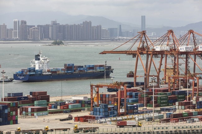A container ship passes in front of containers and gantry cranes at Haitian Container Terminal, operated by the Xiamen Port Authority, in Xiamen, China, Aug. 26, 2019. [File Photo: VCG]