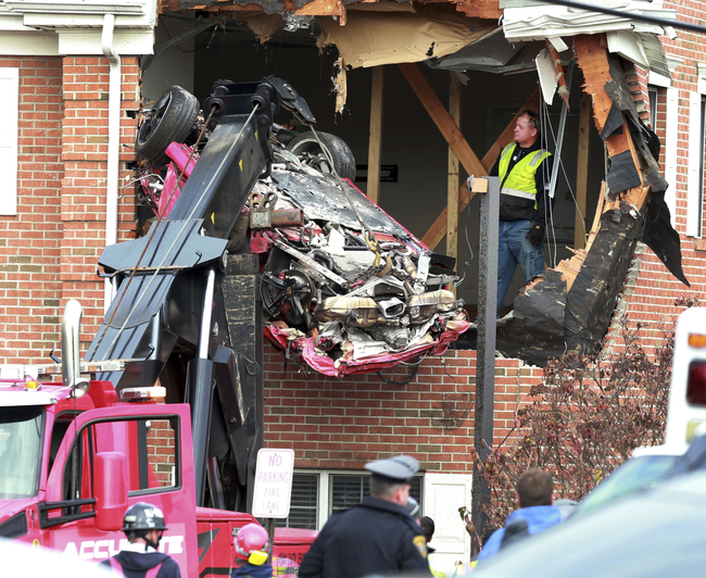 A Porsche is removed form the second story of a building after the convertible went airborne and crashed into the second floor of a New Jersey commercial building early Sunday, killing both of the car's occupants, in Toms River, N.J. [Photo: AP/Ed Murray/NJ Advance Media]