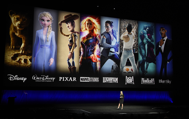 In this April 3, 2019, file photo characters from Disney and Fox movies are displayed behind Cathleen Taff, president of distribution, franchise management, business and audience insight for Walt Disney Studios during the Walt Disney Studios Motion Pictures presentation at CinemaCon 2019, the official convention of the National Association of Theatre Owners (NATO) at Caesars Palace in Las Vegas. On Tuesday, Nov. 12, Disney Plus launches its streaming service. [Photo: AP]