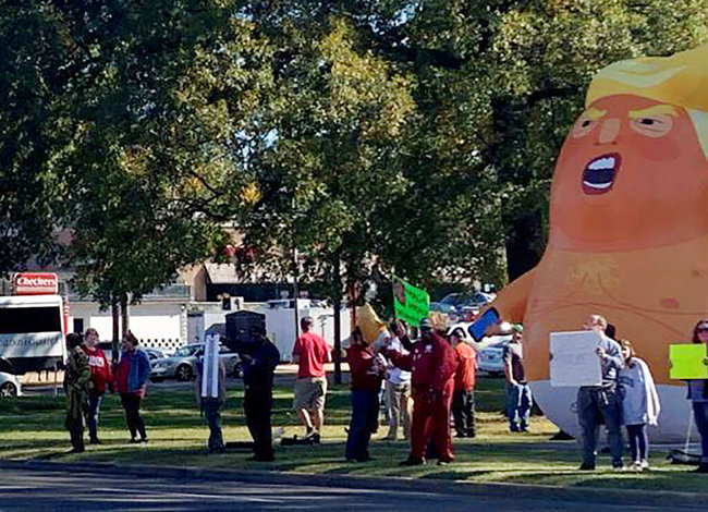 People standing by a Baby Trump balloon at Monnish Park protest President Donald Trump's visit to an NCAA college football game between Louisiana State and Alabama playing nearby in Tuscaloosa, Ala., Saturday, Nov. 9, 2019. [Photo: AP]