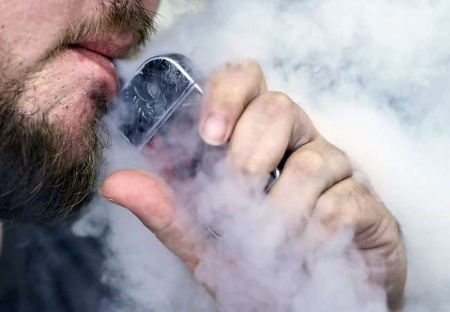 In this Friday, Oct. 4, 2019, file photo, a man using an electronic cigarette exhales in Mayfield Heights, Ohio. On Tuesday, Nov. 19, 2019, the American Medical Association said it is calling for an immediate ban on all electronic cigarette and vaping devices. [Photo: AP]