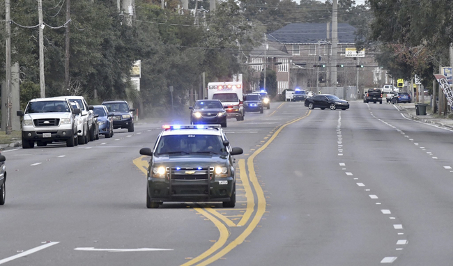 Police cars escort an ambulance after a shooter open fire inside the Pensacola Air Base, Friday, Dec. 6, 2019 in Pensacola, Fla. The US Navy is confirming that a shooter is dead and several injured after gunfire at the Naval Air Station in Pensacola. [Photo: Tony Giberson/ Pensacola News Journal via AP]