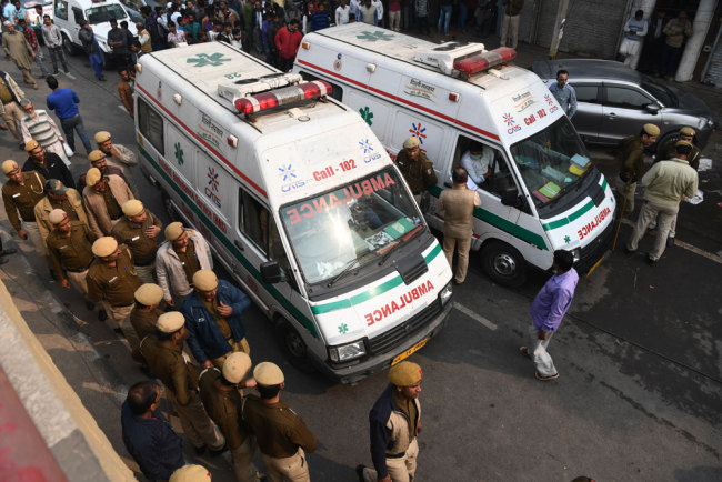 Police personnel and ambulances are seen along a road following a factory fire in Anaj Mandi area of New Delhi on December 8, 2019. [Photo: AFP/Sajjad Hussain]